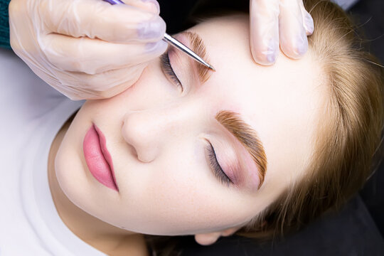close-up of the model's face, the master applies a special hair dye to the eyebrows after the lamination procedure