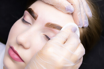 the master removes the remnants of paint from the eyebrows of the model with a cotton sponge