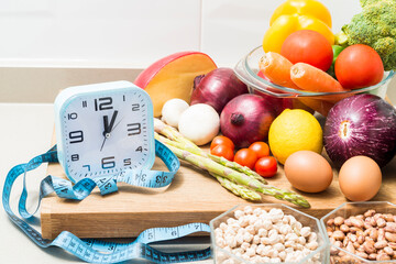 Still life with a clock, a tape measure and healthy food.