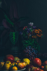 Dark baroque renaissance style still life photography of fruit and flowers. Apples, grapes, pomegranate, quince, mint and garden flowers.
