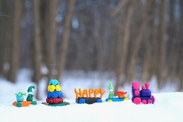 Obraz premium Toy train with Christmas toys made of plasticine in the winter forest. Holiday decorations.