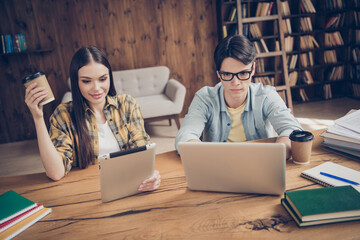 Portrait of two focused friends friendship watching lesson tutorial video drinking latte at loft...