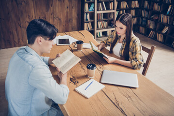 Portrait of two attractive creative focused people doing task reading science book at library loft...