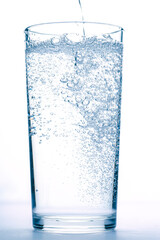 mineral water pours into a glass on a white background