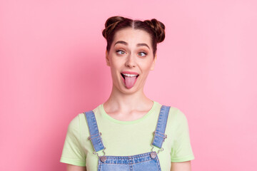 Photo of funky foolish girl grimace crossed eyes protrude tongue wear jeans overall green t-shirt...