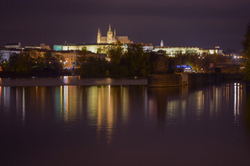 Prague Castle at night, street lights reflected in the water surface, beautiful night city
