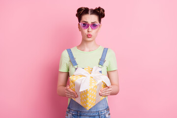 Photo of cute girl hold present box send air kiss wear sunglass jeans overall green t-shirt...