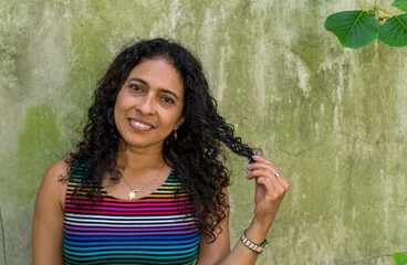 Portrait of Latin woman with wavy hair wearing striped clothes and green background