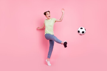 Photo of crazy funky fan lady play football leg kick ball wear green t-shirt jeans sneakers isolated on pink background - obrazy, fototapety, plakaty