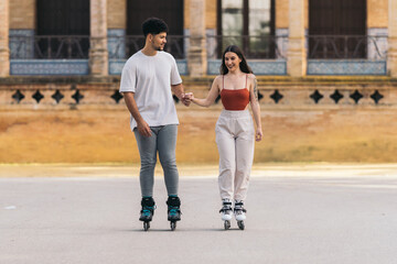 Young couple skating holding hands in a paved park