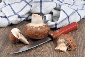 Champignons de Paris bruns crus à côté d'un couteau et d'un torchon
