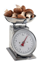 Champignons de Paris bruns crus sur une balance de cuisine en gros plan sur fond blanc