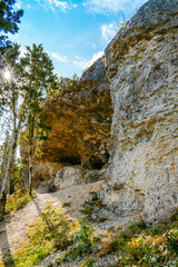 Fototapeta na wymiar Uugu bluff or cliff on the Muhu Island in Estonia, located by the Baltic sea and near the island of Saaremaa. Beautiful sunny day with blue sky, white clouds, forest and stone cliffs by the seaside.