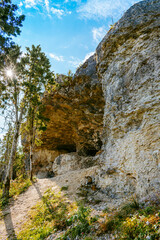 Uugu bluff or cliff on the Muhu Island in Estonia, located by the Baltic sea and near the island of Saaremaa. Beautiful sunny day with blue sky, white clouds, forest and stone cliffs by the seaside.
