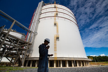 Male workers works permit industry visual inspection of the big white tanks for gas propane
