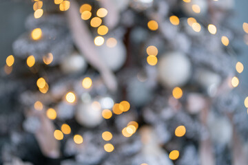 blurred with boke close-up of snowy christmas tree, decorated balls, glowing garland, burning candles, snowballs. Happy New Year. Christmas background with white, gray, yellow, color