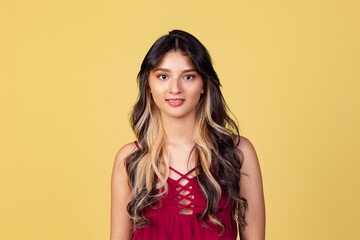 Close-up portrait of young beuatiful girl, student in bright red top isolated on yellow studio backgroud.