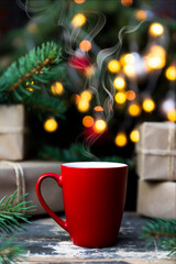 Fototapeta na wymiar Coffee in a red cup on the rustic table with wrapped gifts, Christmas tree lights and spruce branches in the background
