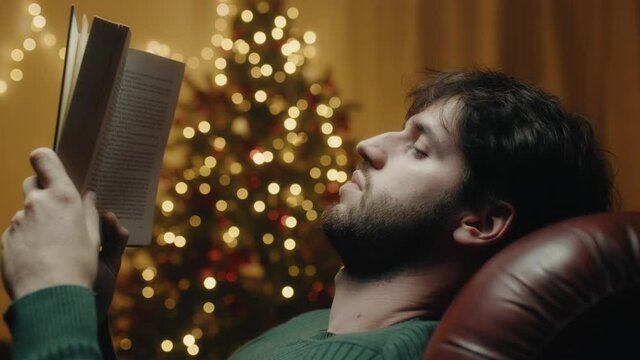 Ragazzo legge libro seduto di fianco all'albero di Natale