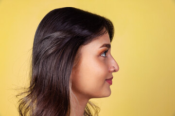 Side view of young beuatiful girl, student in bright red top isolated on yellow studio backgroud.