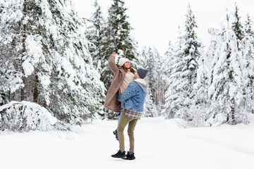 Fototapeta na wymiar man and woman walking and making fun in winter forest