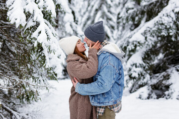 Fototapeta na wymiar love and romance concept - man and woman kissing in winter forest