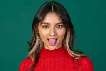 Fototapeta premium Close-up portrait of young beuatiful girl, student in bright red sweater isolated on green studio backgroud.