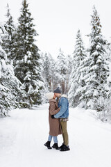 man and woman in love kissing in snowy forest