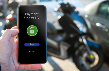 Man's hand pays the rental of motorcycle with application on his phone