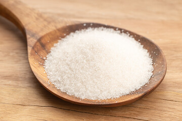 Sugar In Wooden Spoon on wooden table. Close up
