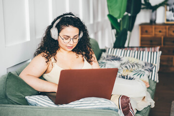 Beautiful overweight woman with laptop ay home.