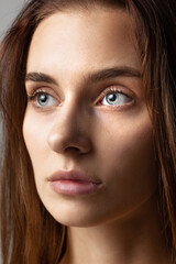 Fototapeta premium Close-up face of young beautiful girl without makeup isolated over gray studio background. Natural beauty concept.