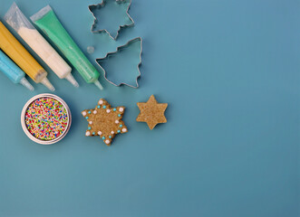 Colored sugar decoration and steel cookie cutters on a blue background. Tubes of paint, small...