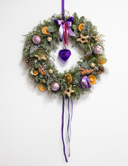 New Year's door wreath decorated with lilac balls and ribbon, cinnamon sticks, and dried orange slices.