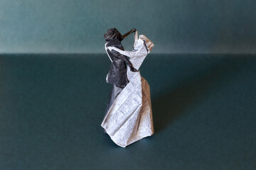 Origami dancing couple figure on a bluish green backgrund. Romantic and beautiful origami bride and...