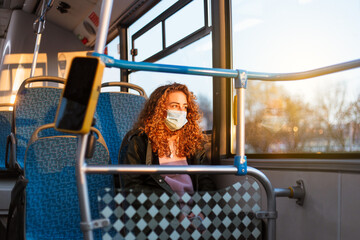 Young woman with respiratory mask traveling in the public transport by bus