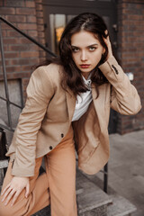  Tall stylish girl with oversized jacket posing near the railing and steps on the city background