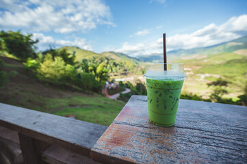 Close up green tea with mountain range view on the wooden balcony.