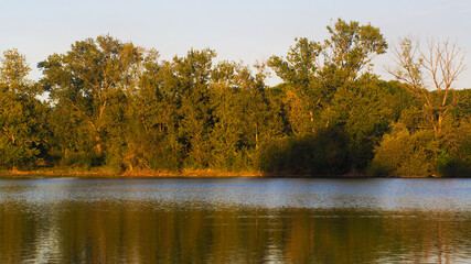 Rives du lac de pêche de Nerbis, non loin de la ville de Mugron.  Il est mis en valeur par un radieux coucher de soleil