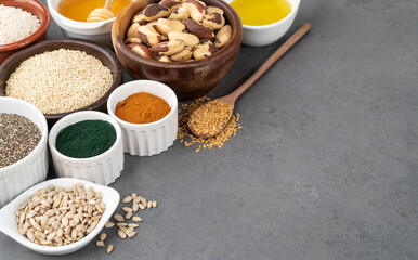 Assorted superfoods in spoons over stone background with copy space. Chia, quinoa, oat, linseed, honey, spirulina and others
