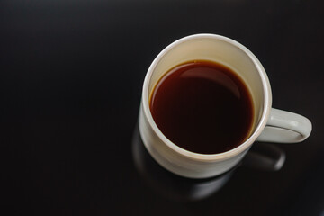 Black coffee in a white ceramic cup on a gray background a place for an inscription. Side view, top view. Selective focus.
