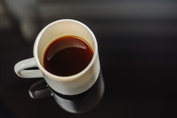 Black coffee in a white ceramic cup on a gray background a place for an inscription. Side view, top view. Selective focus.