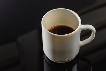 Black coffee in a white ceramic cup on a gray background a place for an inscription. Side view, top view. Selective focus.