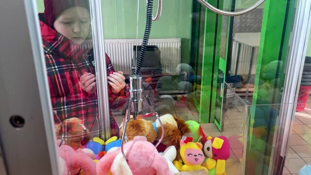 little caucasian girl playing claw game with soft toys grabbing in the mall. Unsuccessful attempt to win a prize, loss, lifestyle