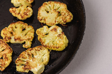 Vegetarian food. Grilled cauliflower steak on a cast iron skillet, top view, close-up view.