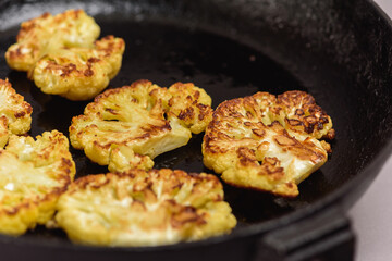 Vegetarian food. Grilled cauliflower steak on a cast iron skillet, top view, close-up view.