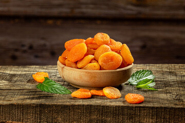 Dried apricots in a wooden bowl on a wooden retro board