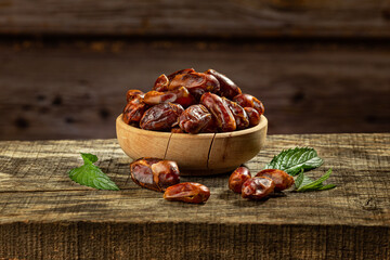 Dried dates in a wooden bowl on a wooden retro board