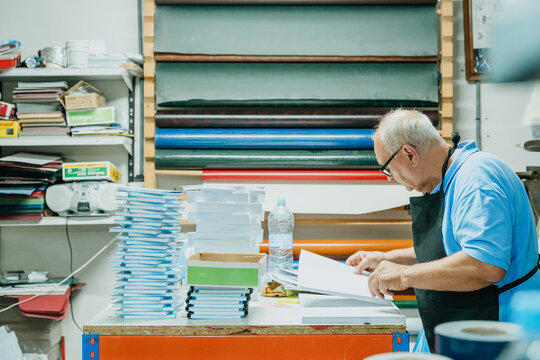 Attentive elderly male worker checking papers in printing studio