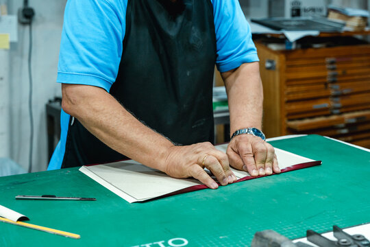Crop artisan folding book cover in printing workshop